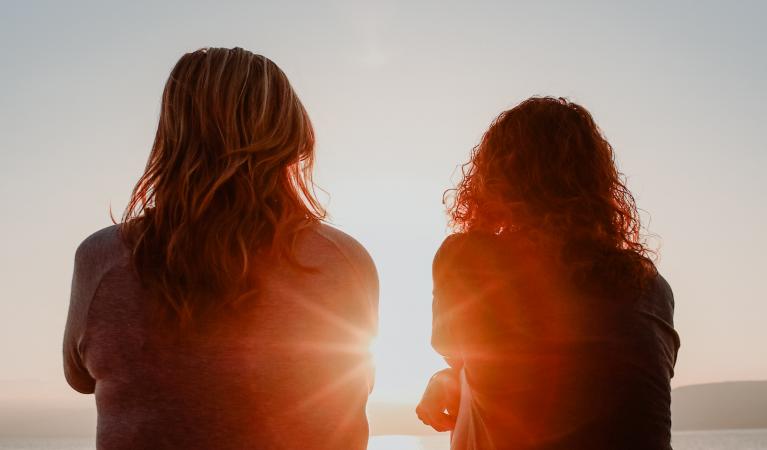 Kahden naisen siluetti ja auringonlasku.