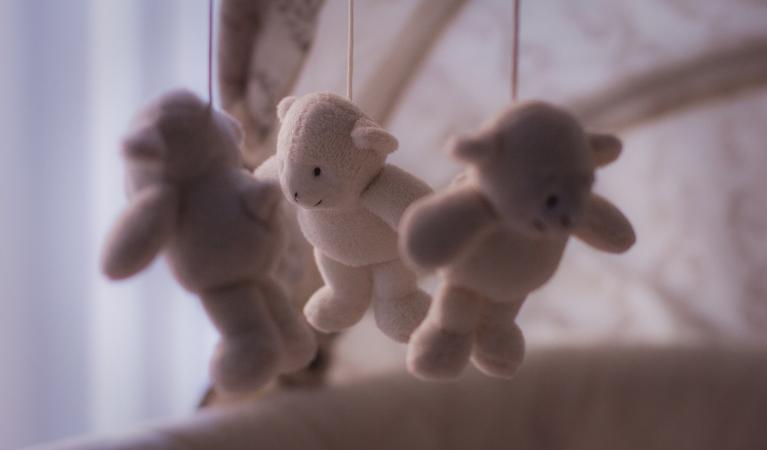 Mobile toy for babies with three soft toys hanging from it.