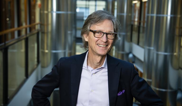 Hymyilevä Aarno Palotie seisomassa portaikossa.