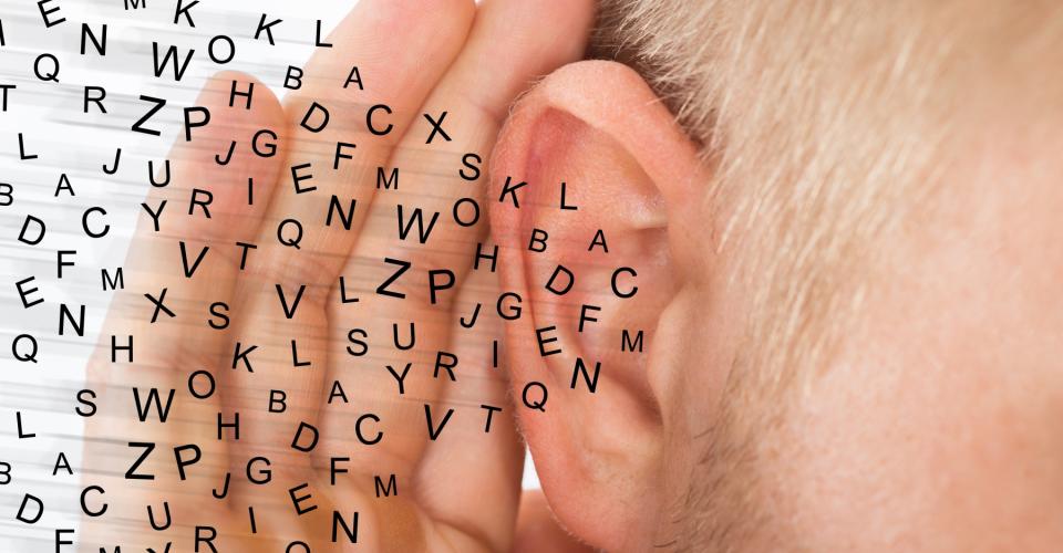 A person trying to hear, with a hand over the ear.