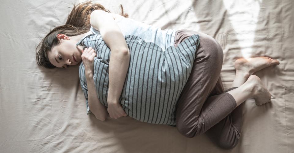 Young woman alone in the morning is lying in bed and hugging a pillow.