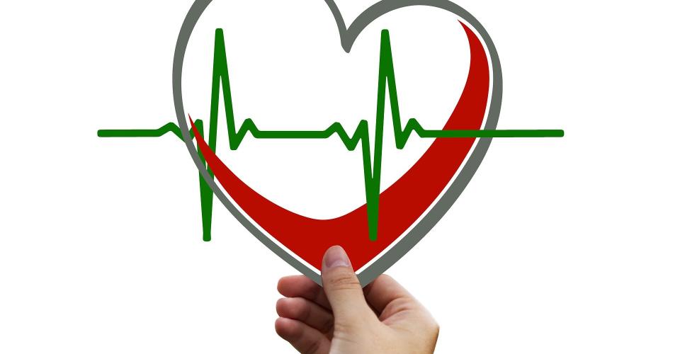 Hand holding a heart-shaped graphic with an ECG line.